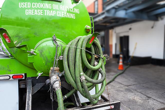 a grease trap being pumped by a sanitation technician in Wayland MA